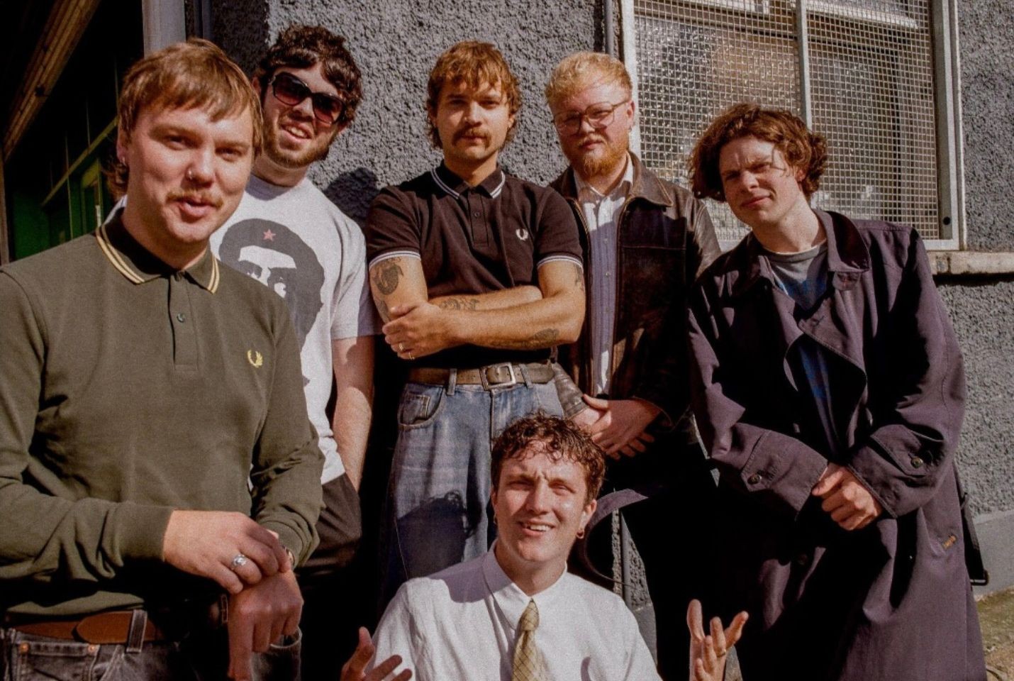 Madra Salach stood in front of a grey building